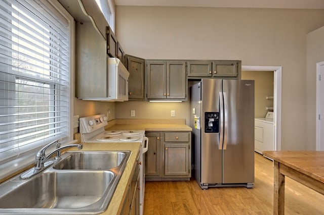 kitchen featuring sink, light hardwood / wood-style flooring, stainless steel appliances, and independent washer and dryer