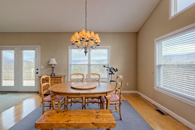 dining area with a wealth of natural light, light hardwood / wood-style flooring, a chandelier, and vaulted ceiling