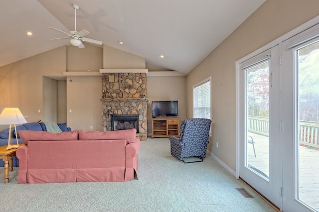 living room featuring carpet floors, vaulted ceiling, ceiling fan, and a stone fireplace