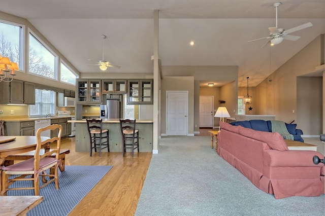 living room with light wood-type flooring, high vaulted ceiling, and ceiling fan