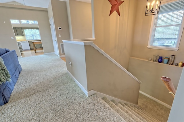 staircase featuring plenty of natural light, carpet floors, and an inviting chandelier