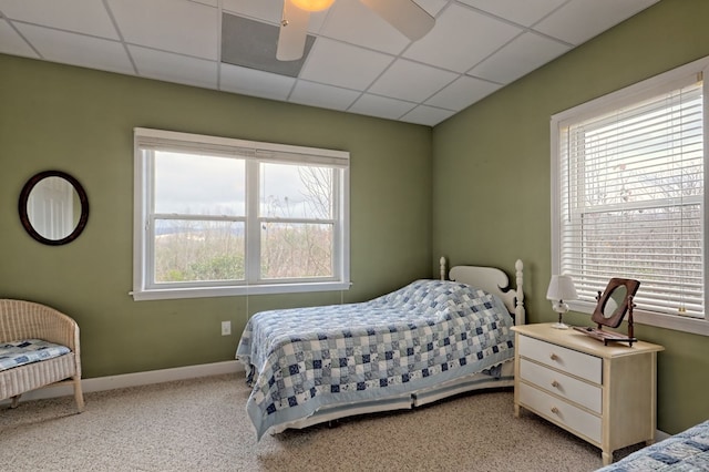 carpeted bedroom with a paneled ceiling and ceiling fan