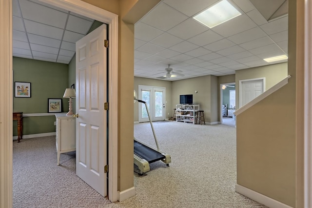 hallway with a drop ceiling, light carpet, and french doors