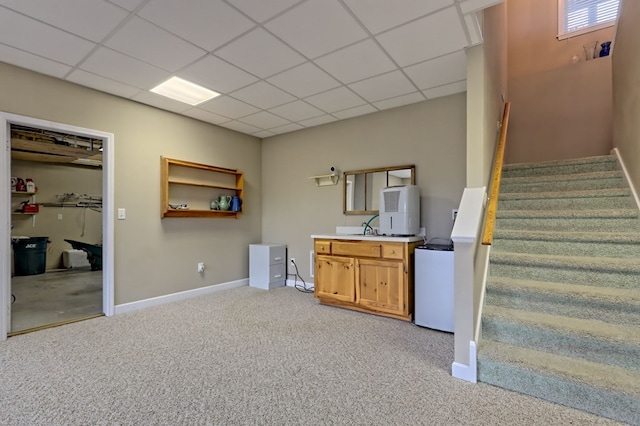 interior space with carpet flooring, a drop ceiling, and sink