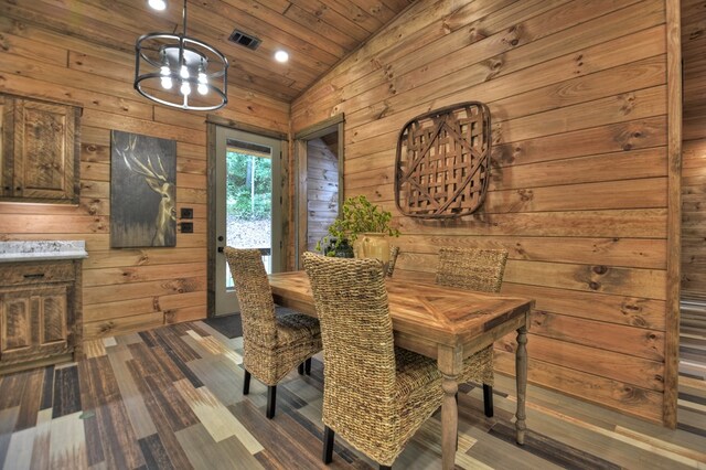 dining area featuring a notable chandelier, wood ceiling, dark wood-type flooring, lofted ceiling, and wooden walls