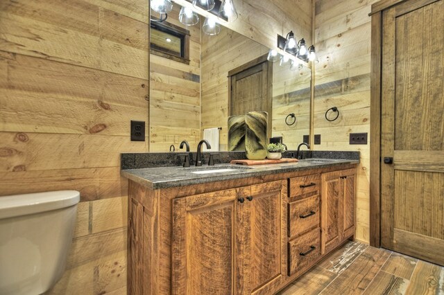 bathroom with toilet, wooden walls, and vanity