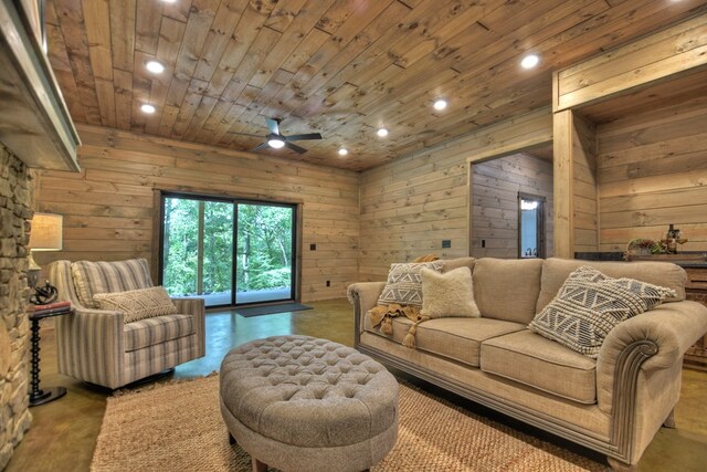 living room with ceiling fan, wooden walls, concrete floors, and wooden ceiling