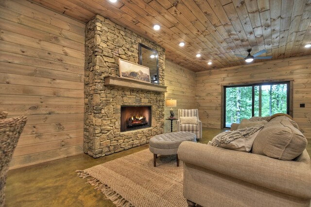 living room featuring a fireplace, wood ceiling, concrete floors, and wooden walls