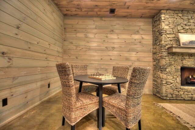 dining area with a fireplace, concrete floors, wooden walls, and wooden ceiling