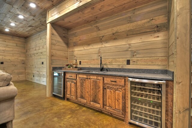 bar with wood walls, wine cooler, and sink