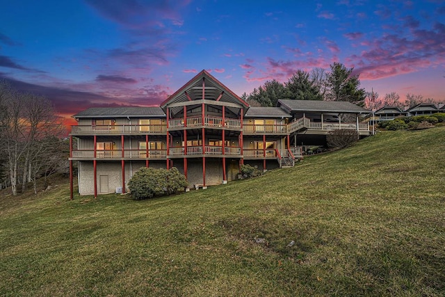 back of property at dusk featuring a yard