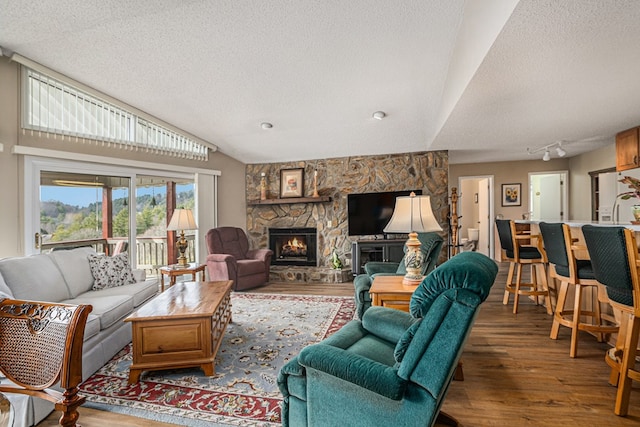 living area with lofted ceiling, a fireplace, a textured ceiling, and wood finished floors