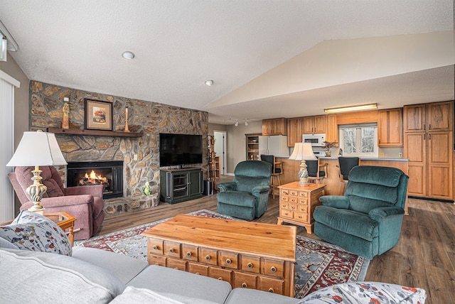 living area featuring a textured ceiling, a fireplace, vaulted ceiling, and dark wood-type flooring