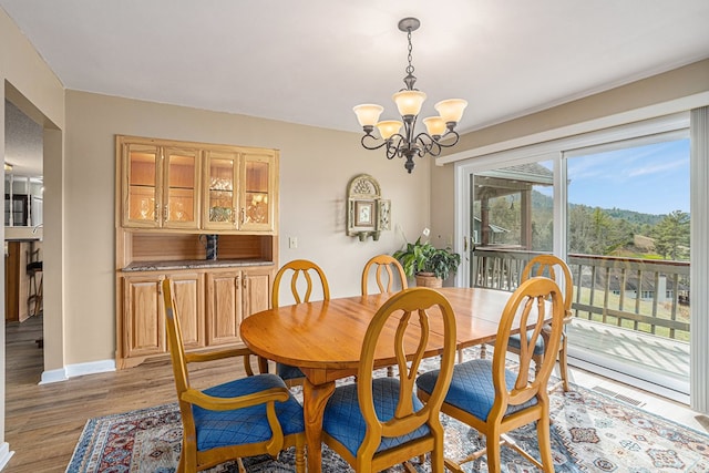 dining space featuring a notable chandelier, light wood-style flooring, and baseboards