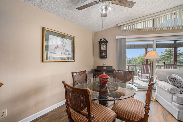 dining area featuring baseboards, a ceiling fan, lofted ceiling, wood finished floors, and a textured ceiling