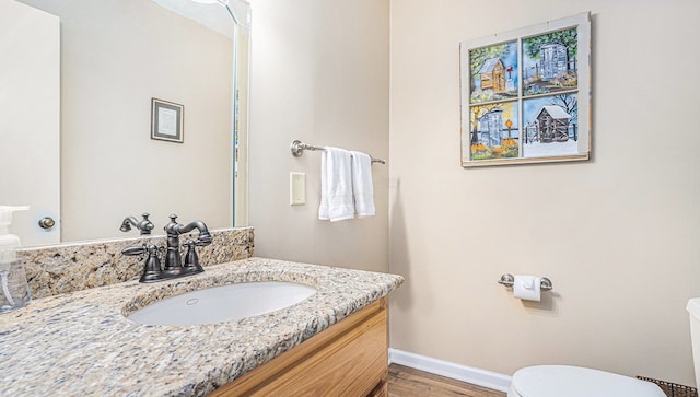 bathroom with vanity, wood finished floors, toilet, and baseboards