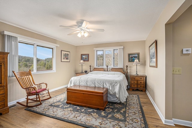 bedroom with multiple windows, visible vents, baseboards, and wood finished floors