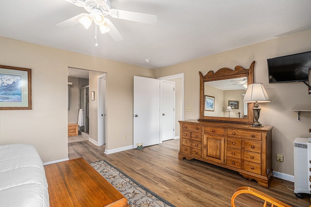 bedroom with a ceiling fan, ensuite bath, baseboards, and wood finished floors