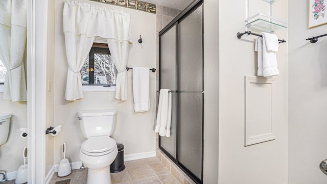 full bath featuring baseboards, a shower stall, toilet, and tile patterned floors