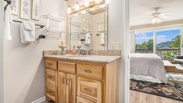 ensuite bathroom featuring connected bathroom, ceiling fan, wood finished floors, a textured ceiling, and vanity