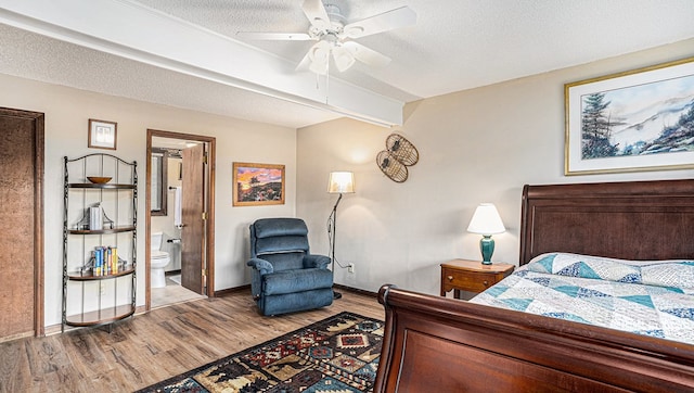 bedroom with baseboards, a ceiling fan, ensuite bath, wood finished floors, and a textured ceiling