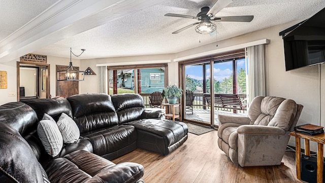 living area with ceiling fan with notable chandelier, a textured ceiling, and wood finished floors