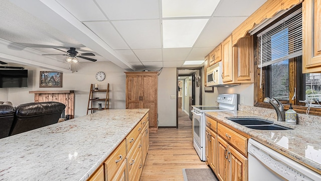 kitchen featuring a paneled ceiling, white appliances, a sink, and light stone countertops