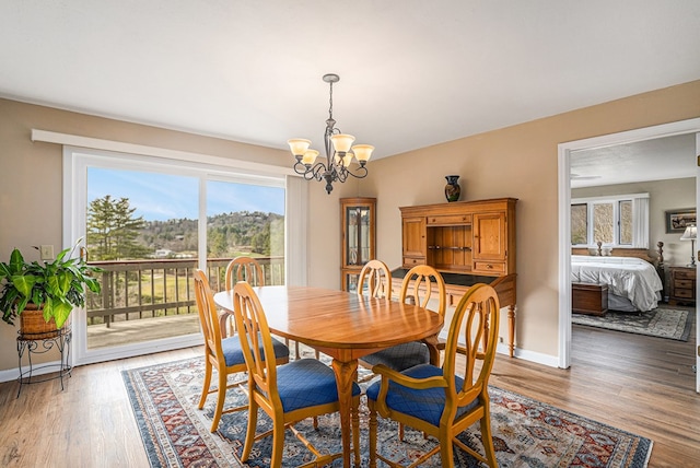 dining space featuring light wood-type flooring, a notable chandelier, and baseboards