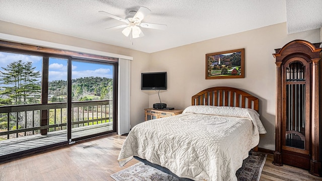 bedroom with access to exterior, a textured ceiling, visible vents, and wood finished floors