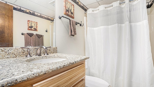 full bathroom featuring a drop ceiling, vanity, toilet, and a shower with curtain