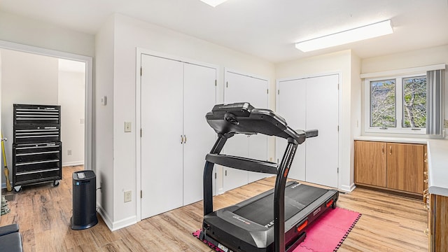 workout room featuring light wood-style flooring and baseboards