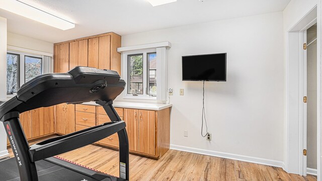 workout area with baseboards and light wood-style floors