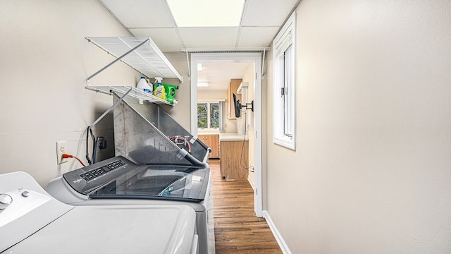 laundry room with laundry area, baseboards, wood finished floors, and washing machine and clothes dryer