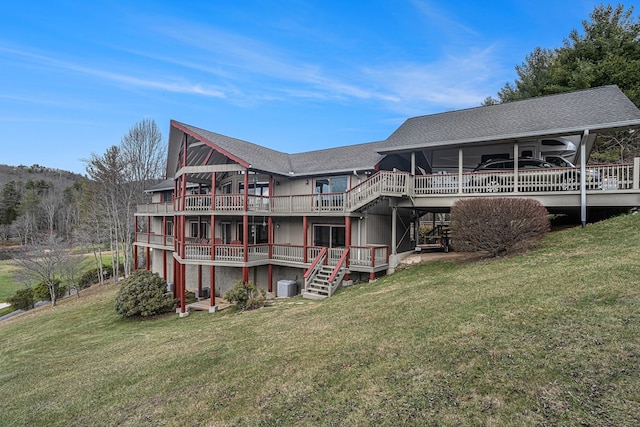 rear view of property featuring a shingled roof, a lawn, stairs, a wooden deck, and central air condition unit