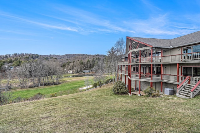 view of yard featuring a forest view, stairway, central AC, and a wooden deck