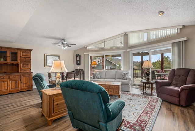 living room featuring vaulted ceiling, ceiling fan, a textured ceiling, and wood finished floors