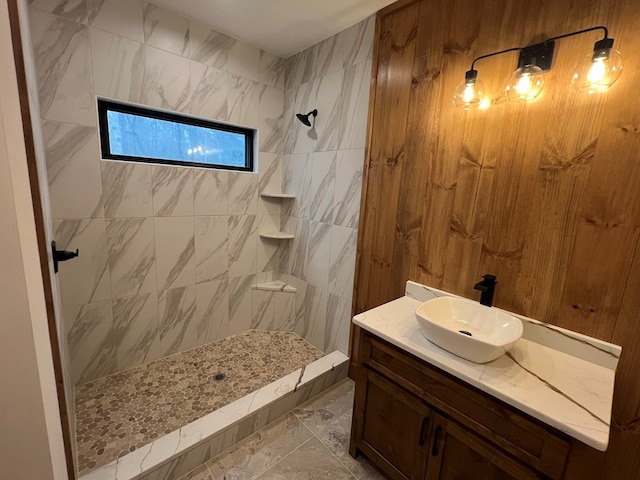 bathroom featuring a tile shower, marble finish floor, and vanity