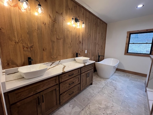bathroom with baseboards, wood walls, a freestanding bath, and a sink