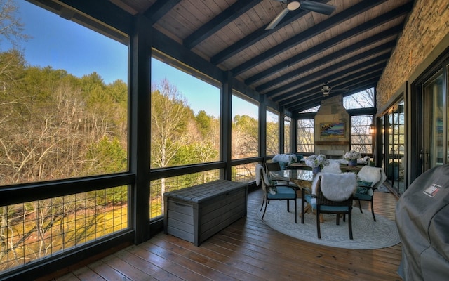 sunroom / solarium with a ceiling fan, beam ceiling, and outdoor dining space