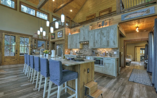 kitchen featuring high vaulted ceiling, dark wood finished floors, wood ceiling, stainless steel microwave, and backsplash