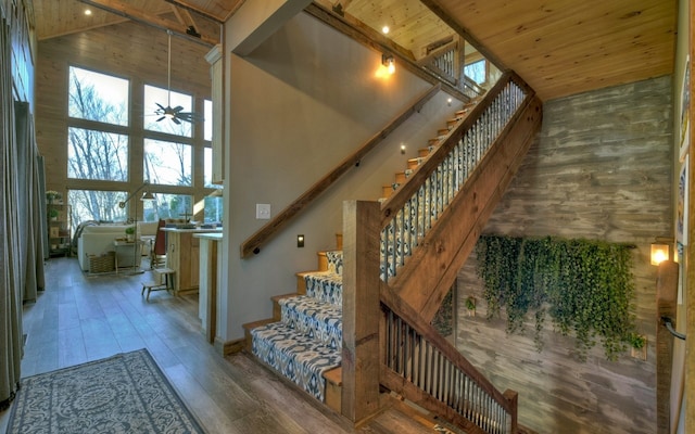 stairway with wood ceiling, a high ceiling, and wood-type flooring
