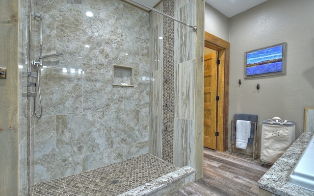 full bath with a tile shower and wood finished floors