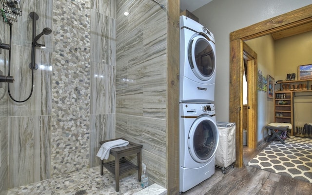 washroom with wood finished floors, stacked washing maching and dryer, and laundry area