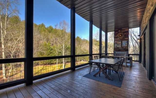 sunroom / solarium with a deck, a wall of windows, outdoor dining area, and wood-type flooring