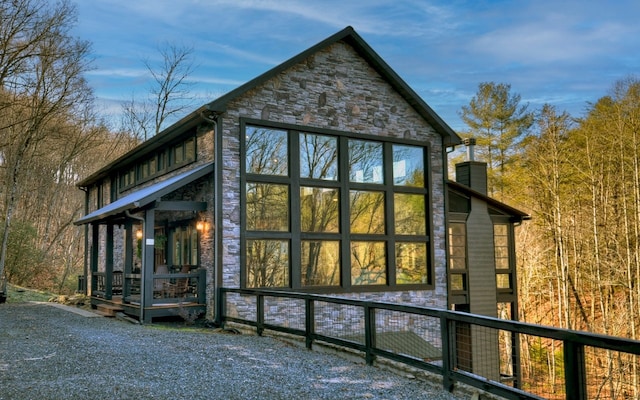 view of side of property featuring a chimney and stone siding