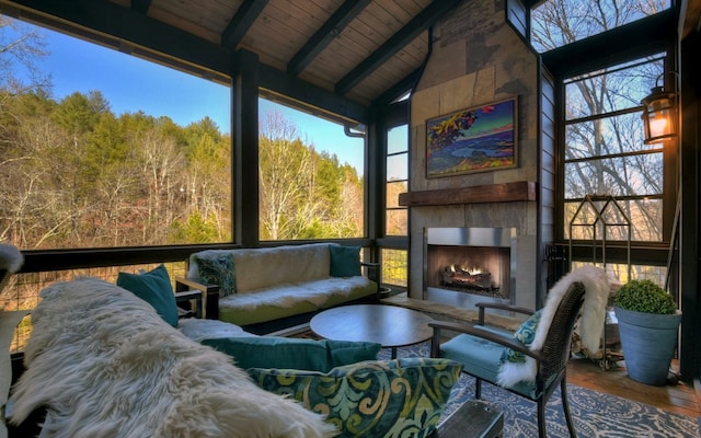 sunroom / solarium with an outdoor living space with a fireplace, a healthy amount of sunlight, and beamed ceiling