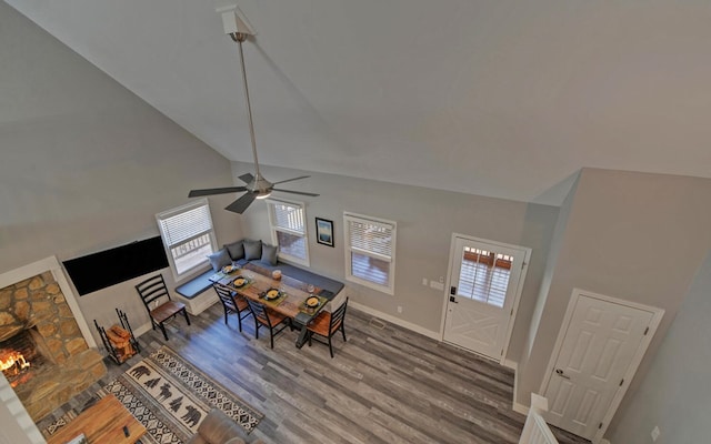 dining space with baseboards, a fireplace, high vaulted ceiling, and wood finished floors