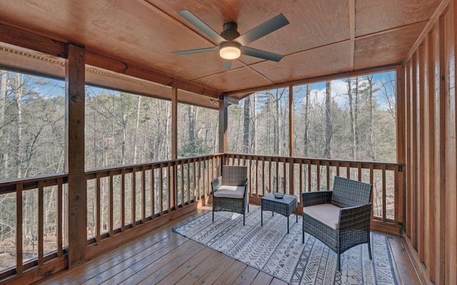 unfurnished sunroom featuring ceiling fan, a forest view, and wood ceiling