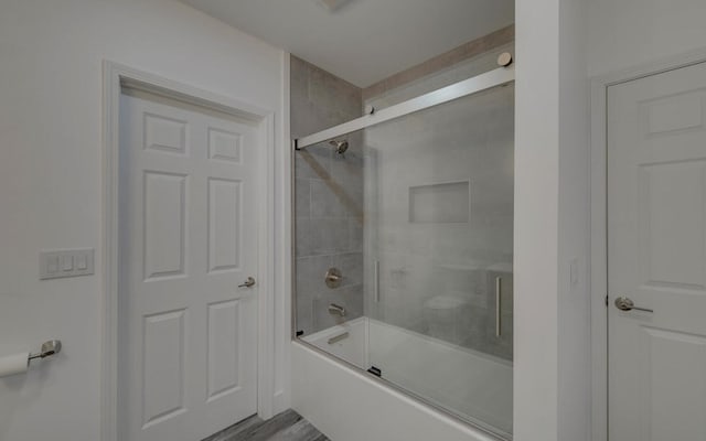 full bathroom with combined bath / shower with glass door and wood finished floors