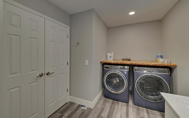 clothes washing area featuring laundry area, separate washer and dryer, wood finished floors, and baseboards